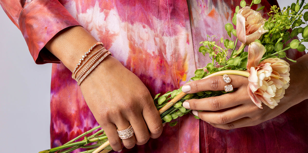 Closeup of diamond bracelets, bangles, rings, and creme-pink-peach silk shirt dress from the collection Spring Edit by Dominique Cohen; call 323-404-2959 for shop help